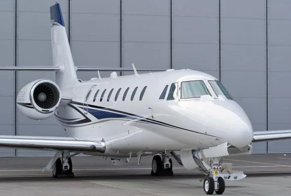 A white and blue jet aircraft is parked on the tarmac.
