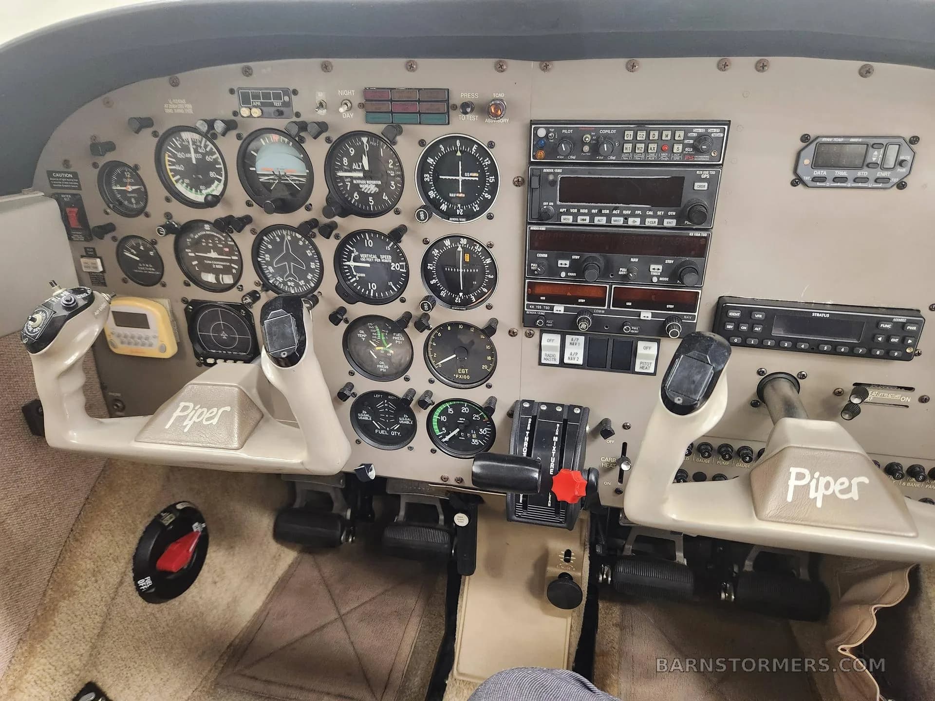 The instrument panel and dual yokes of a Piper aircraft cockpit.
