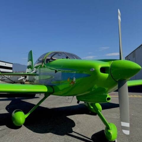 Front view of a green aircraft with blue accents parked on the tarmac.