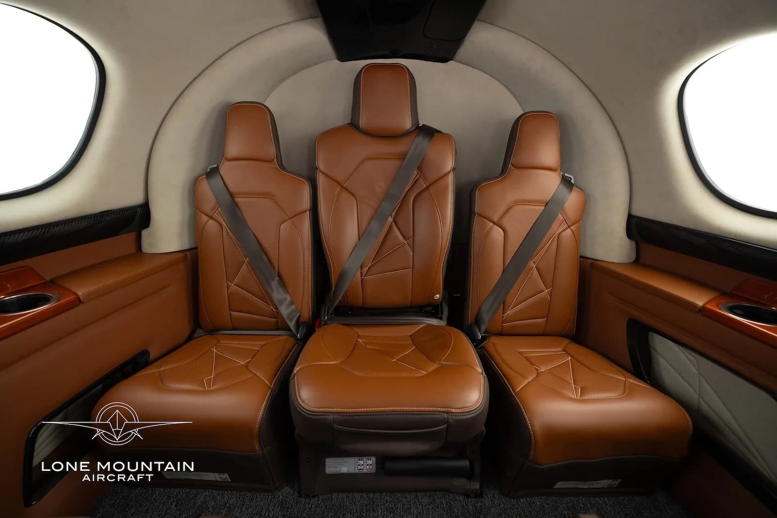 A close-up view of the three brown leather passenger seats in the rear cabin of a Cirrus Vision Jet (SF50).