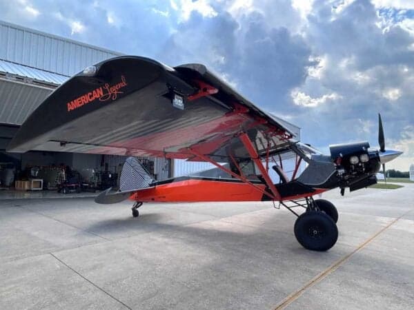 Side view of the American Legend aircraft with a black and orange paint scheme.
