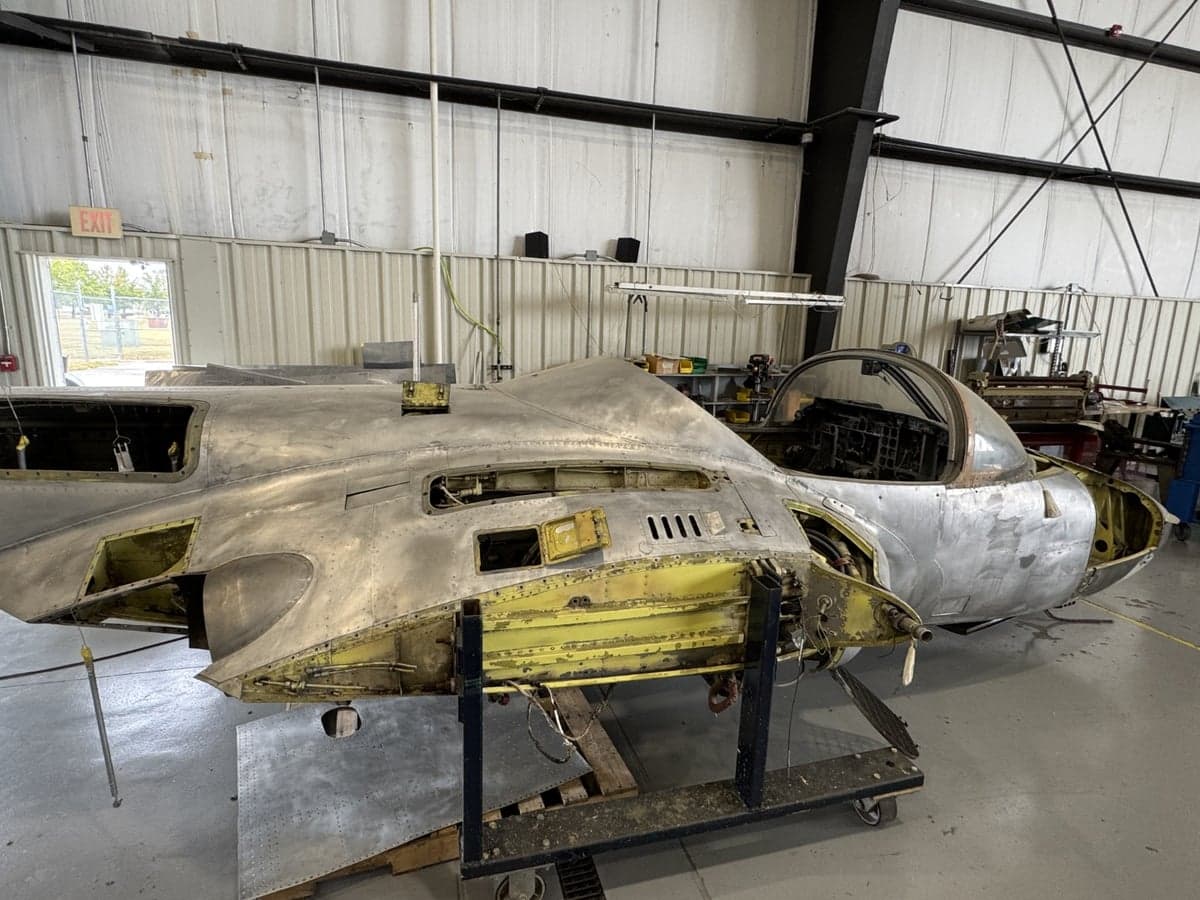 A partially disassembled aircraft in a hangar, showing the cockpit area.