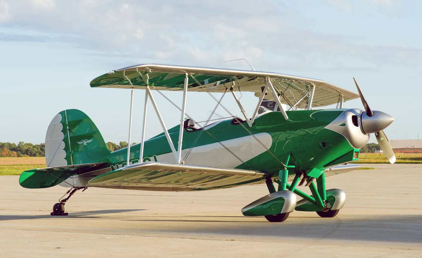 A green and silver biplane sits on the tarmac.
