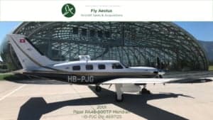 Piper PA-46-500TP Meridian aircraft with registration HB-PJG parked outside a building.