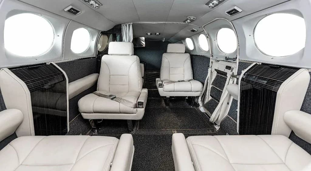 A wider view of the aircraft's cabin interior with light-colored seats and dark patterned walls, looking towards the cockpit.