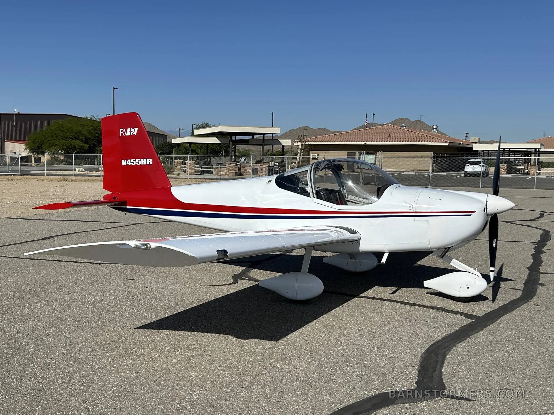 A white and red Van's RV-7 aircraft, registration N455HR, is parked on an asphalt tarmac, viewed from the front-right side.