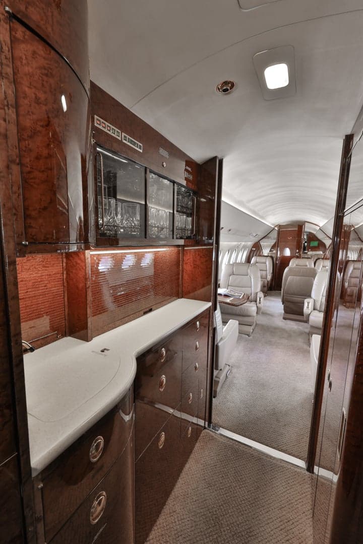View of the aircraft interior with wood paneling and leather seats.