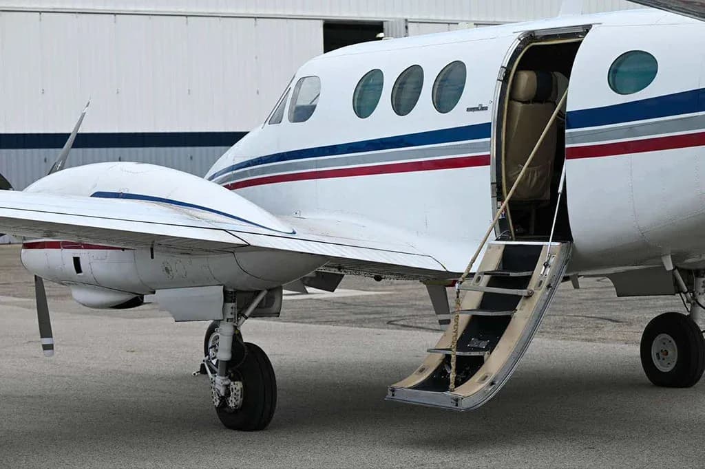 A close-up of the open passenger door and stairs of a white Beechcraft King Air C90GTx.