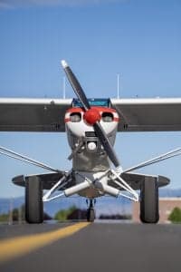 Front view of a Piper Super Cub aircraft with a red and white paint scheme on the runway.
