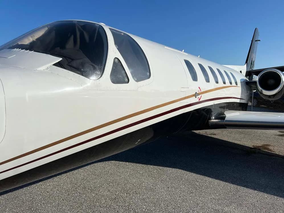 Close up of the fuselage of a white and black jet with gold accent stripes.
