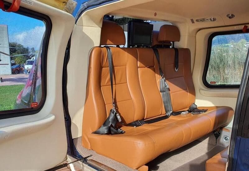 The interior of the helicopter features tan leather seats and a view out the window.