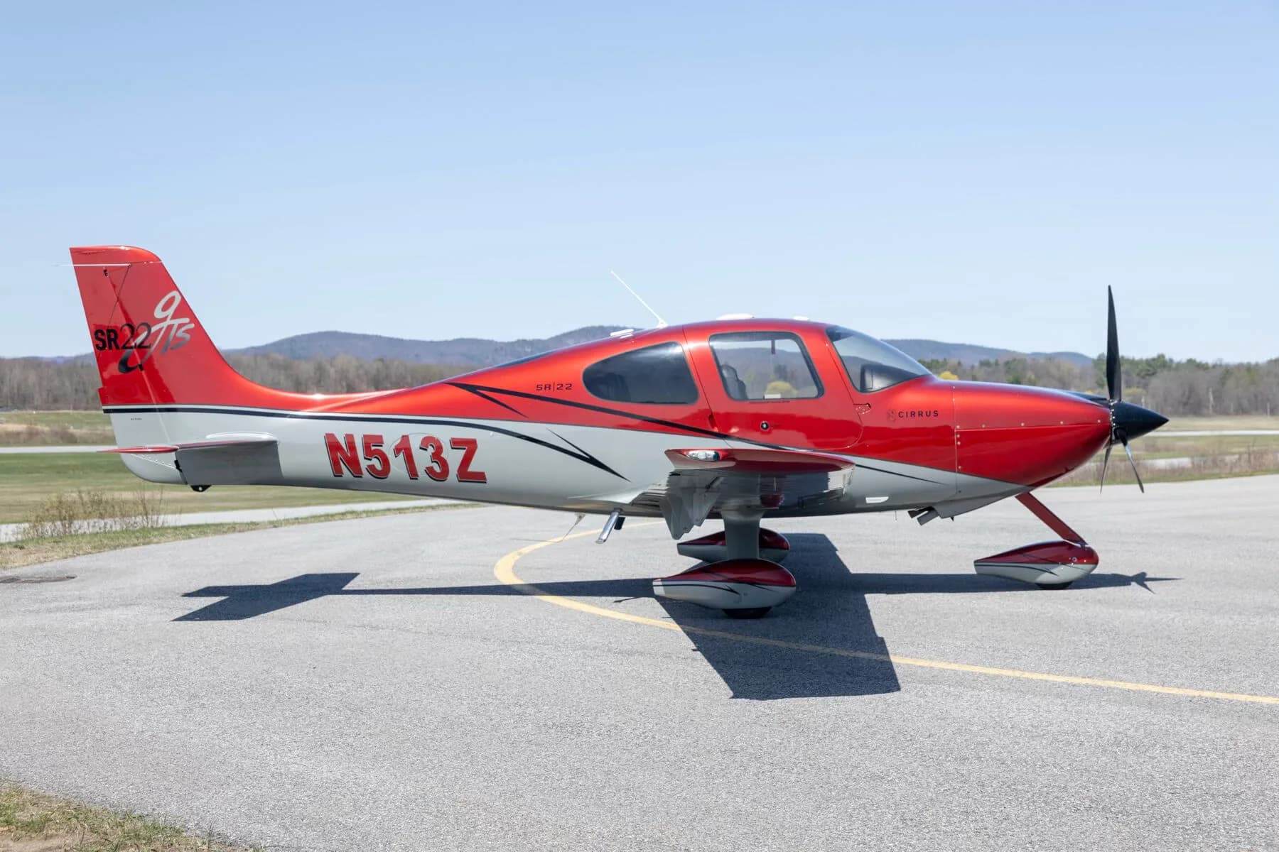 A red and grey Cirrus SR22T aircraft (N513Z) parked on an asphalt runway.
