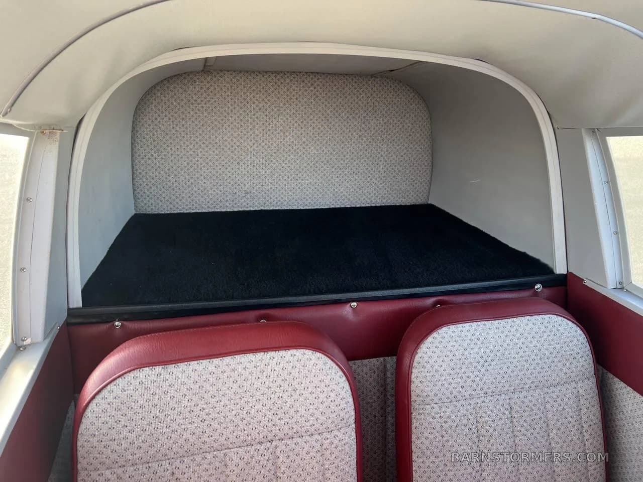 The interior cargo area of a small aircraft, showing a black carpeted floor behind the rear seats.
