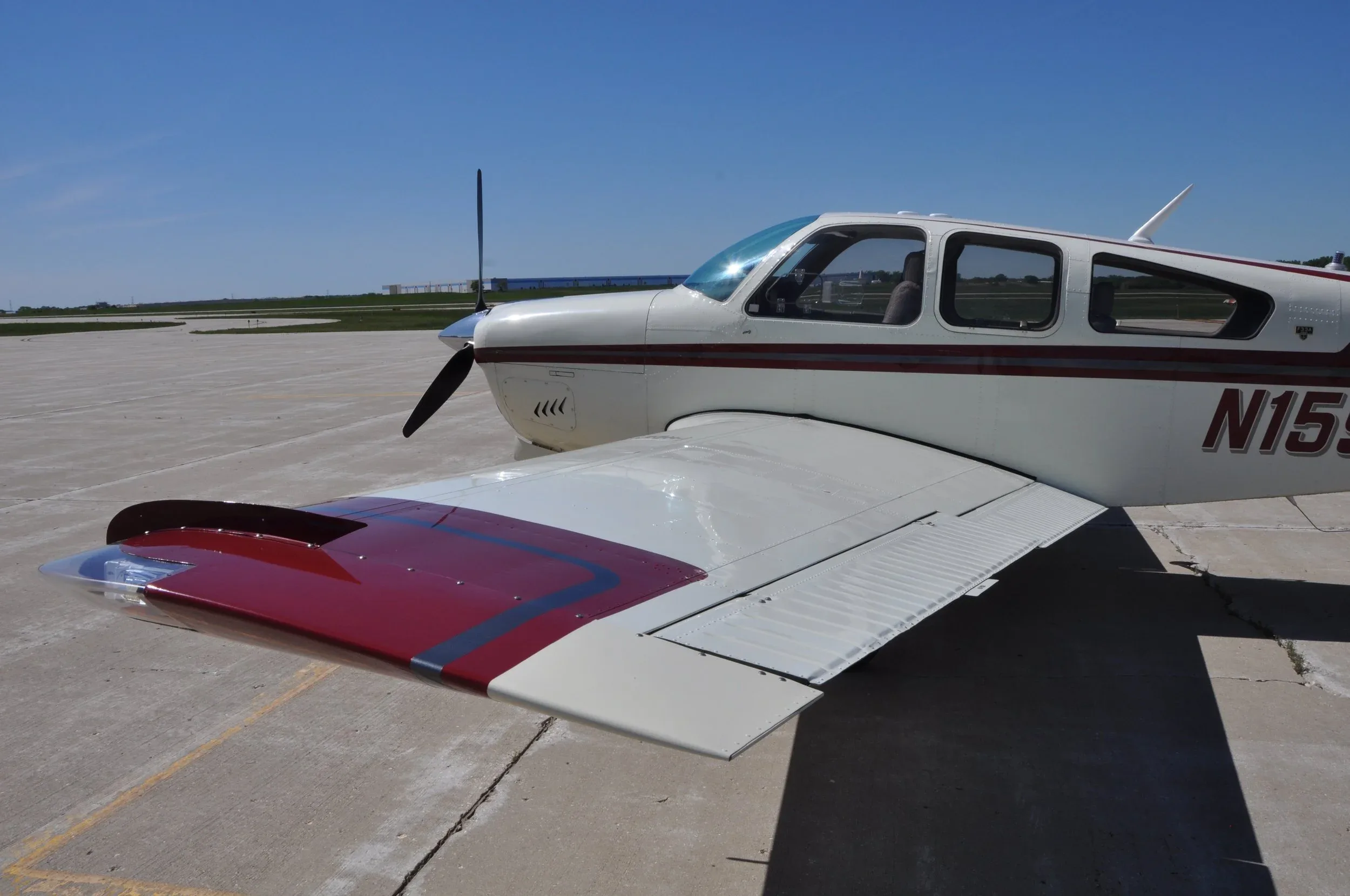 A front-right view of the white and red aircraft, highlighting the wing and propeller.