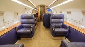 Interior of the Challenger aircraft cabin with leather seats and carpeted floor.
