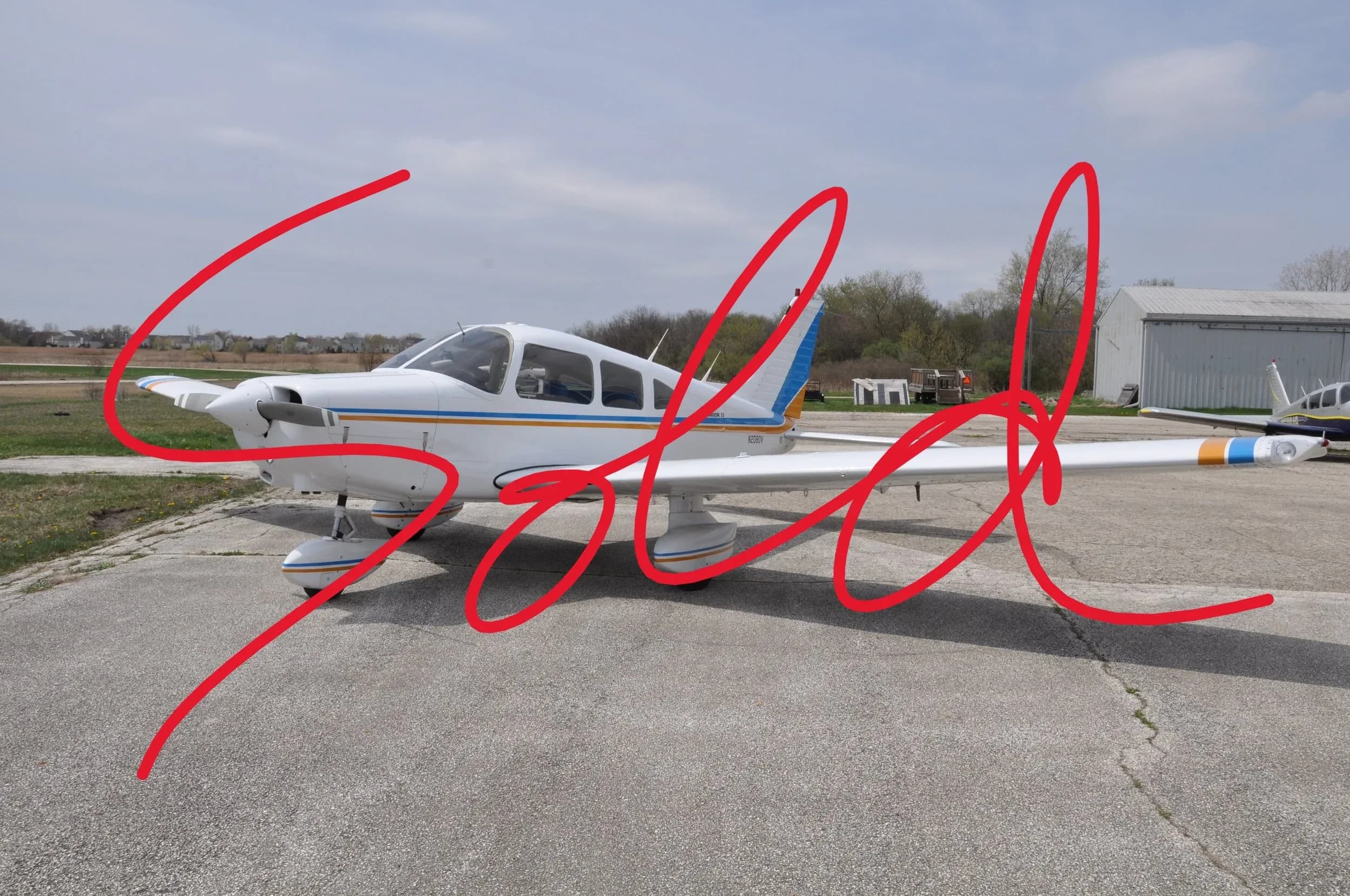 A white single-engine propeller aircraft with blue and orange stripes parked on an asphalt apron.
