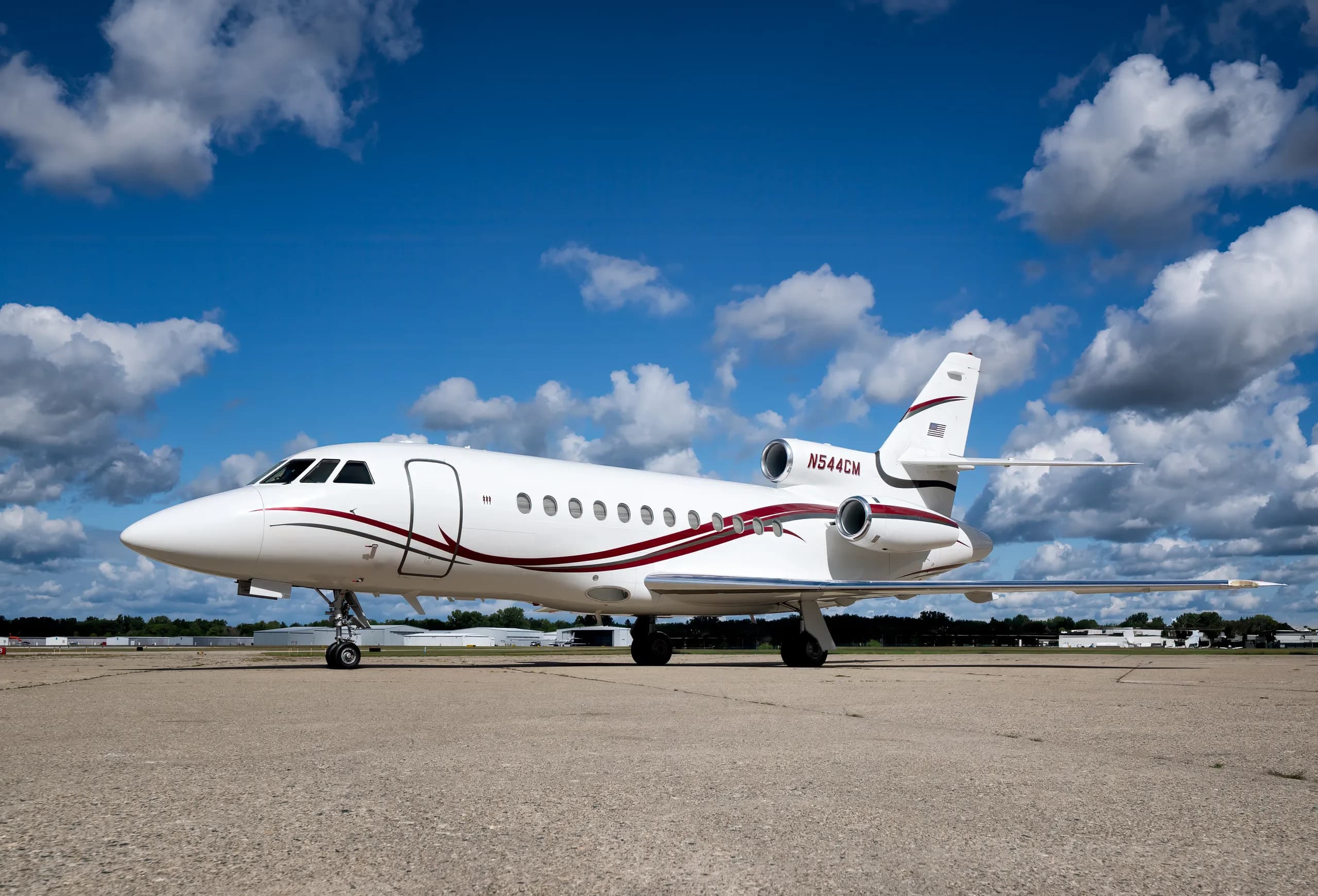 Side view of a white aircraft with red stripes on the tarmac.