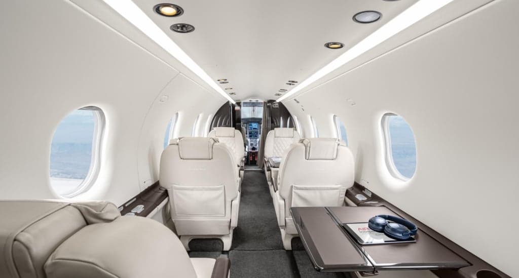 Interior view of the aircraft cabin with white leather seats and a table.