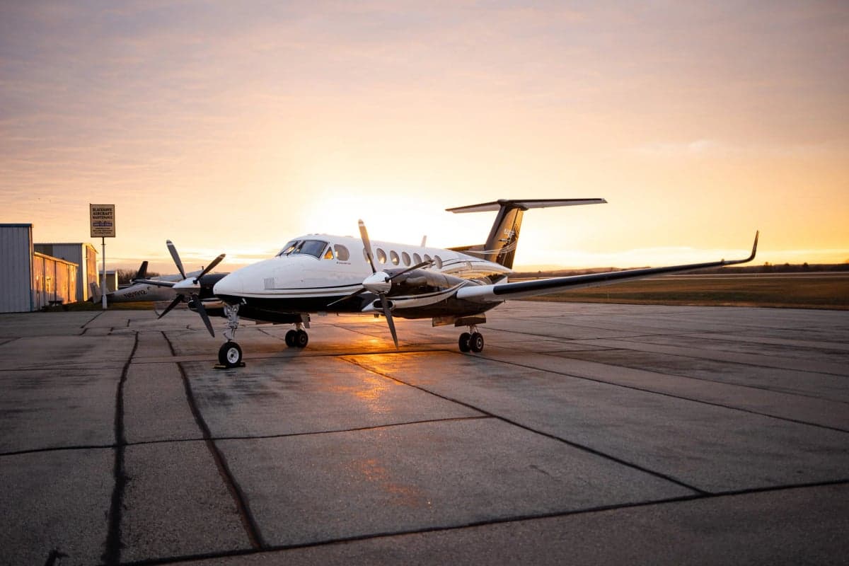 A King Air 350i aircraft is parked on the tarmac at sunset.