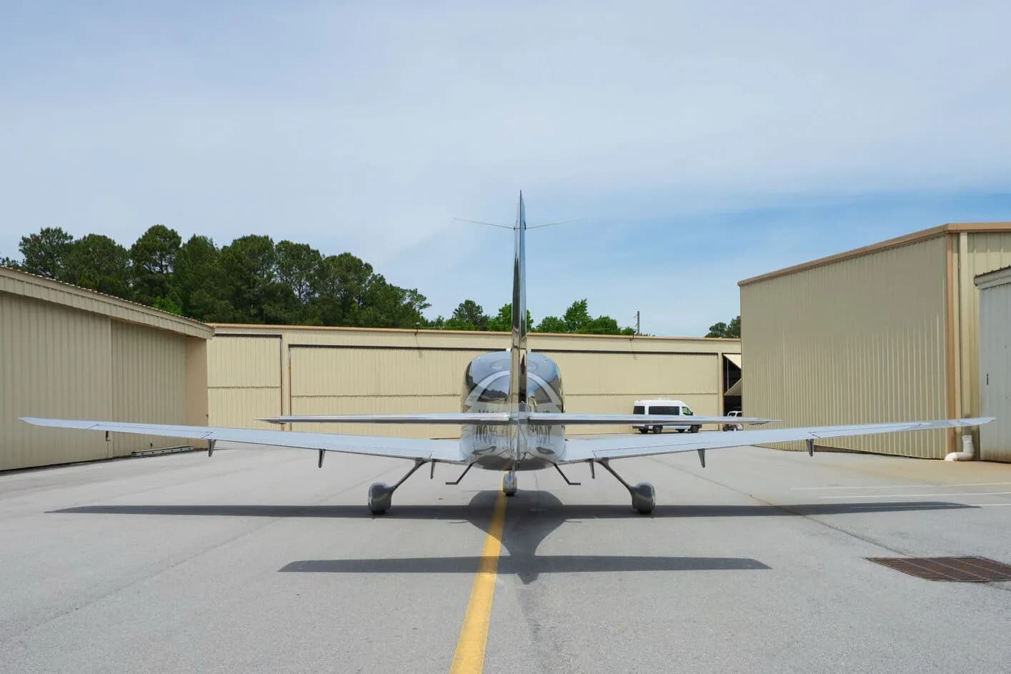 Rear view of a silver Cirrus SR22 aircraft with a T-tail, parked on an airfield.