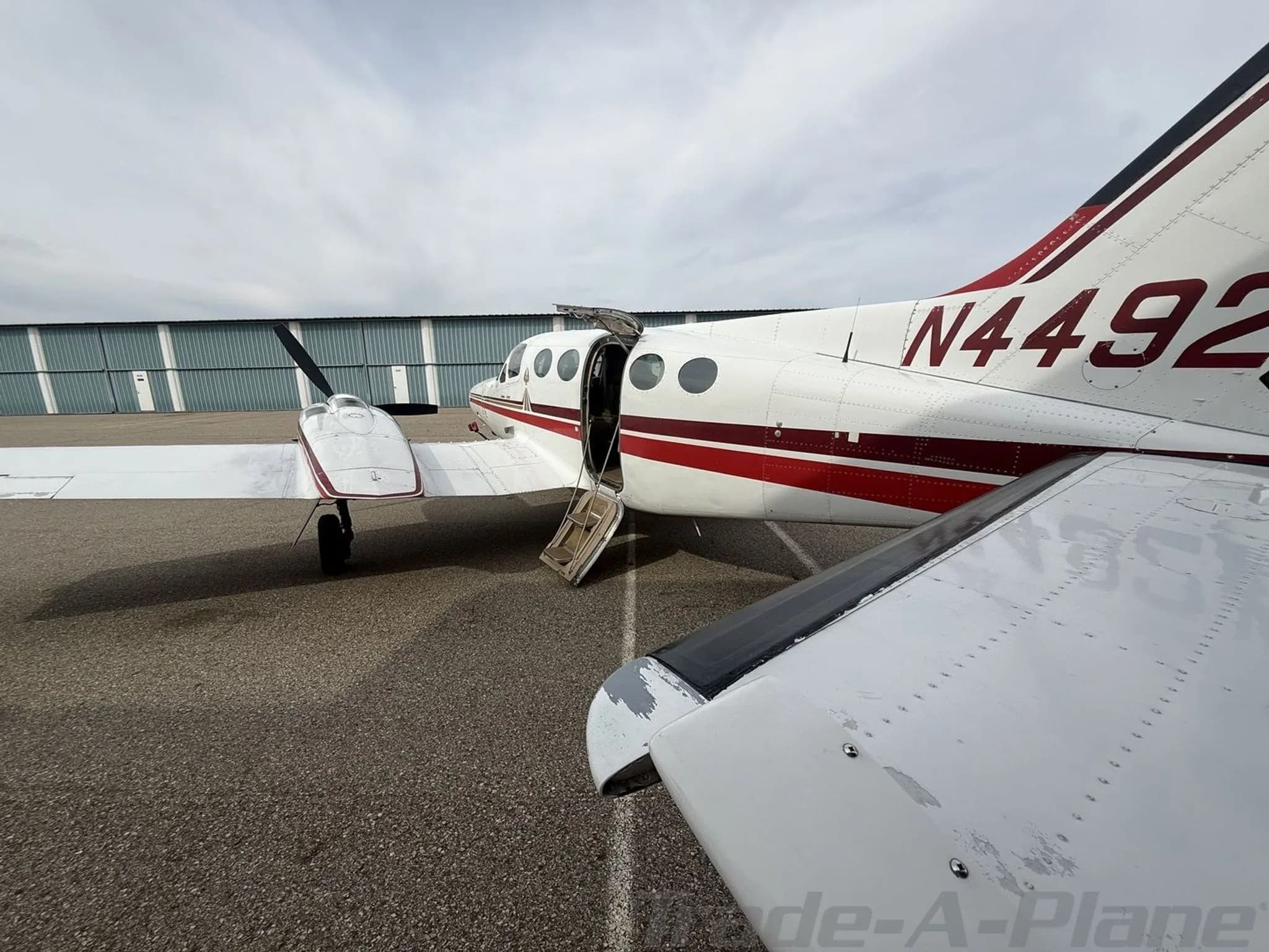 An angled rear view of a white and red twin-engine Cessna 414 Chancellor aircraft, registration N4492U, with its passenger door open.
