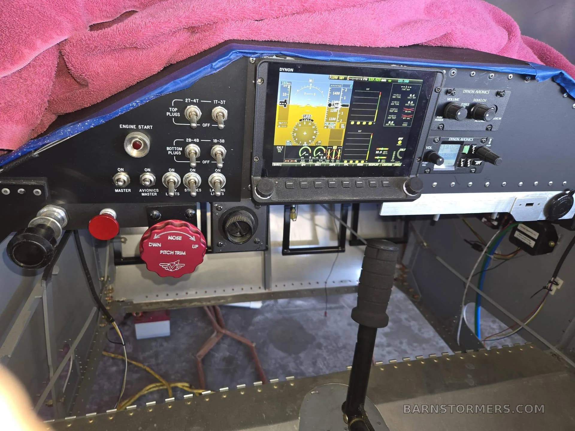 A close-up view of an aircraft cockpit with a large digital display and various controls.