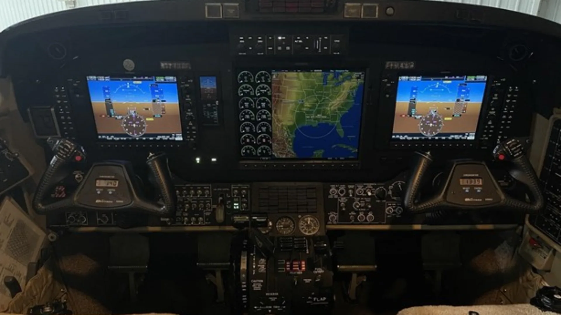 The cockpit of an aircraft featuring a modern glass panel with multiple digital displays showing navigation and flight data.