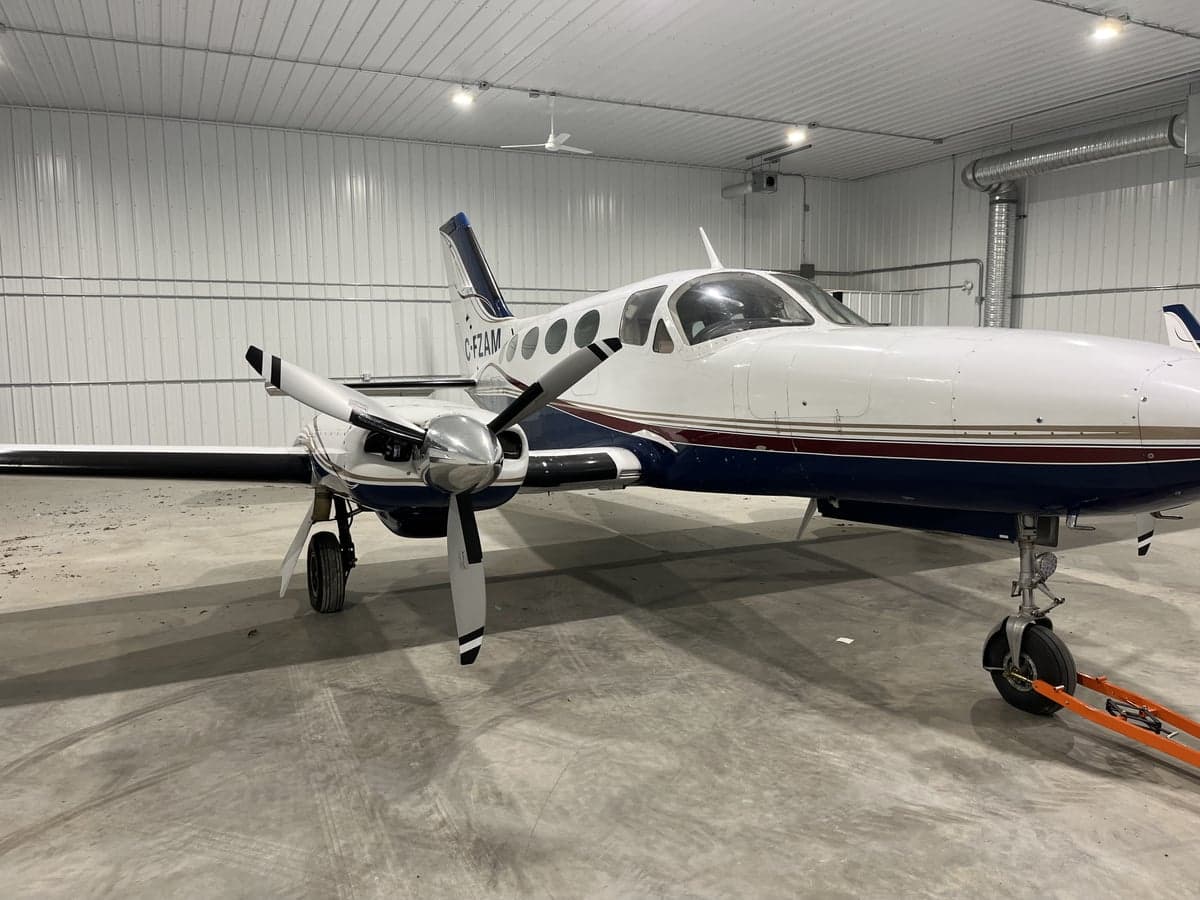 A white and blue twin-engine aircraft is parked in a hangar.