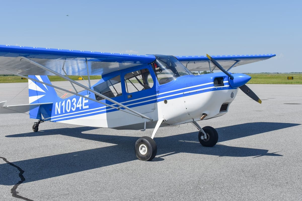 Side view of a blue and white aircraft with tail number N1034E on the tarmac.