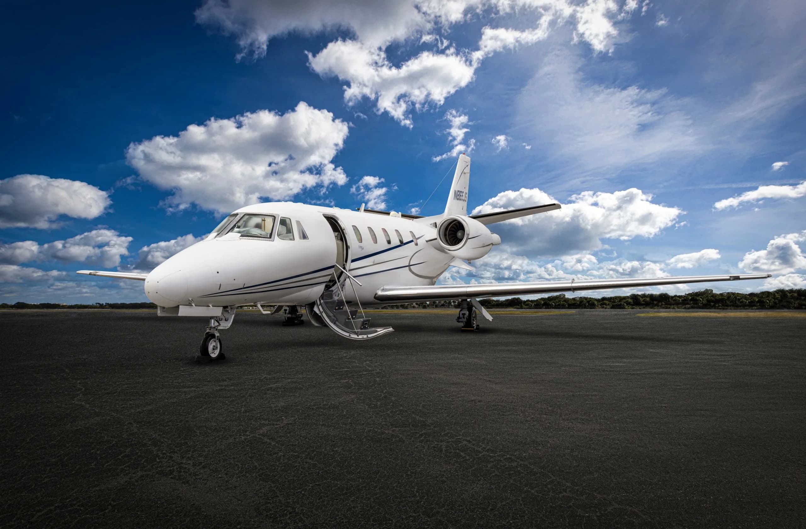 A white aircraft with blue stripes parked on the tarmac with the stairs down.