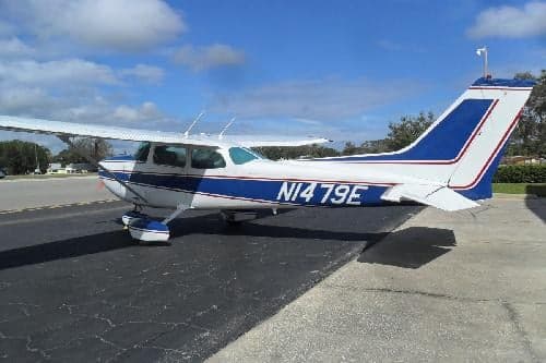 A white and blue Cessna 172 with tail number N1479E is parked on the tarmac.
