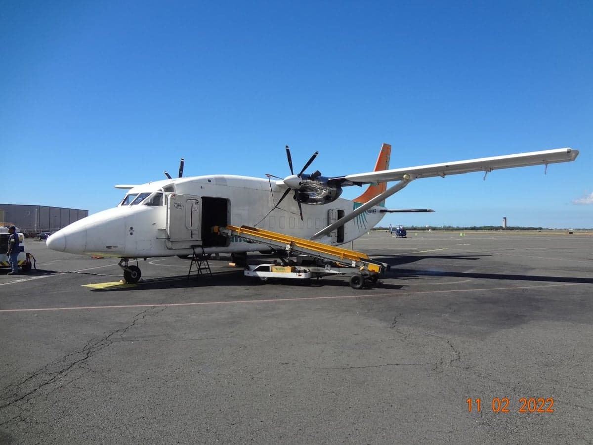 Side view of a white Short 360 aircraft with an open cargo door and a yellow loading ramp at an airport.