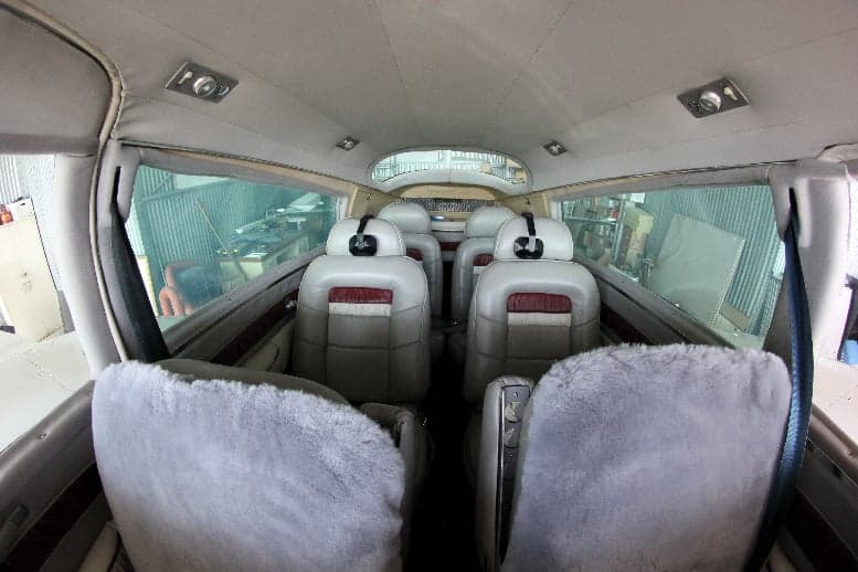 The interior of the aircraft features gray leather seats with red accents.
