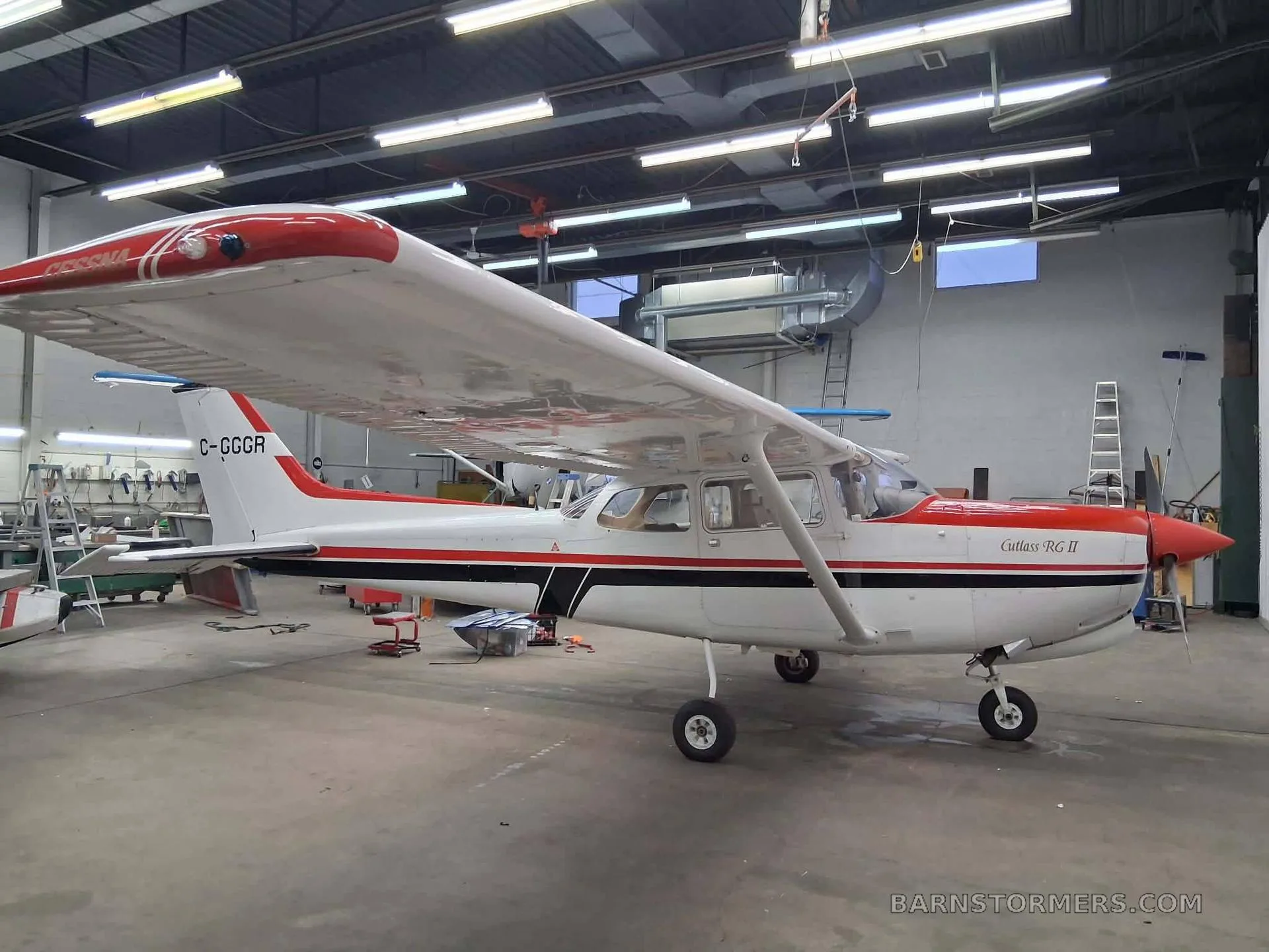 A white and red Cessna Cutlass RG II (C-GGCR) parked in a hangar.