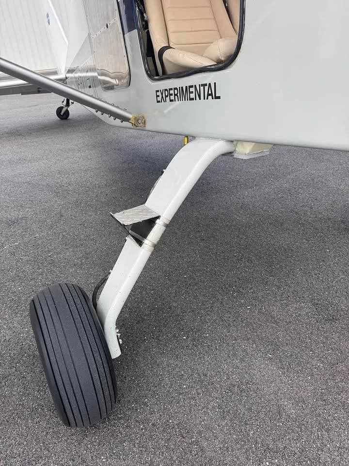 A close-up view of the nose landing gear and the "EXPERIMENTAL" marking on the fuselage of the aircraft.