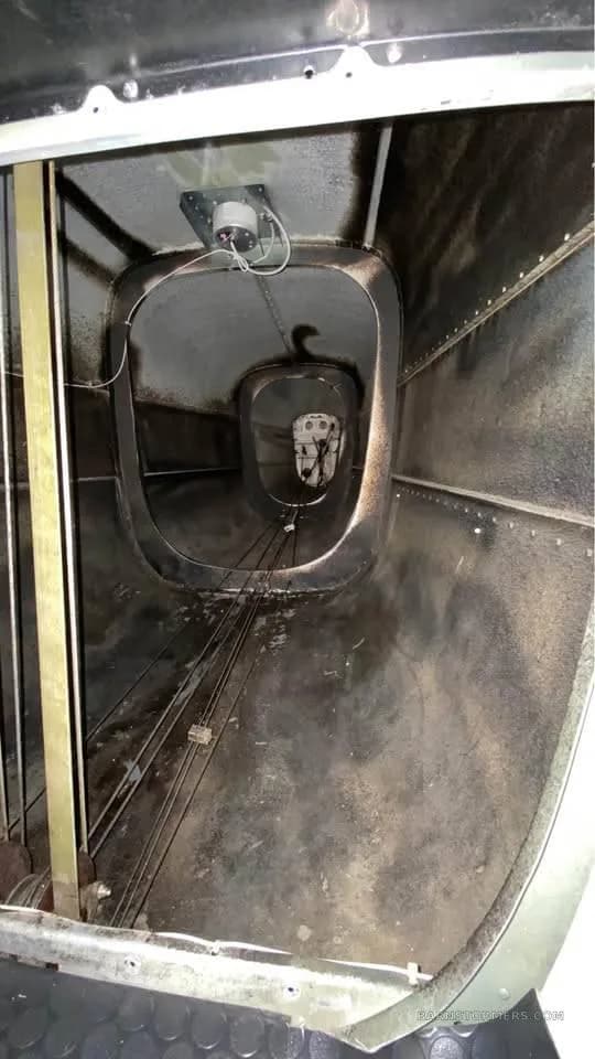 View inside an aircraft's structural bay, showing control cables and internal framework.