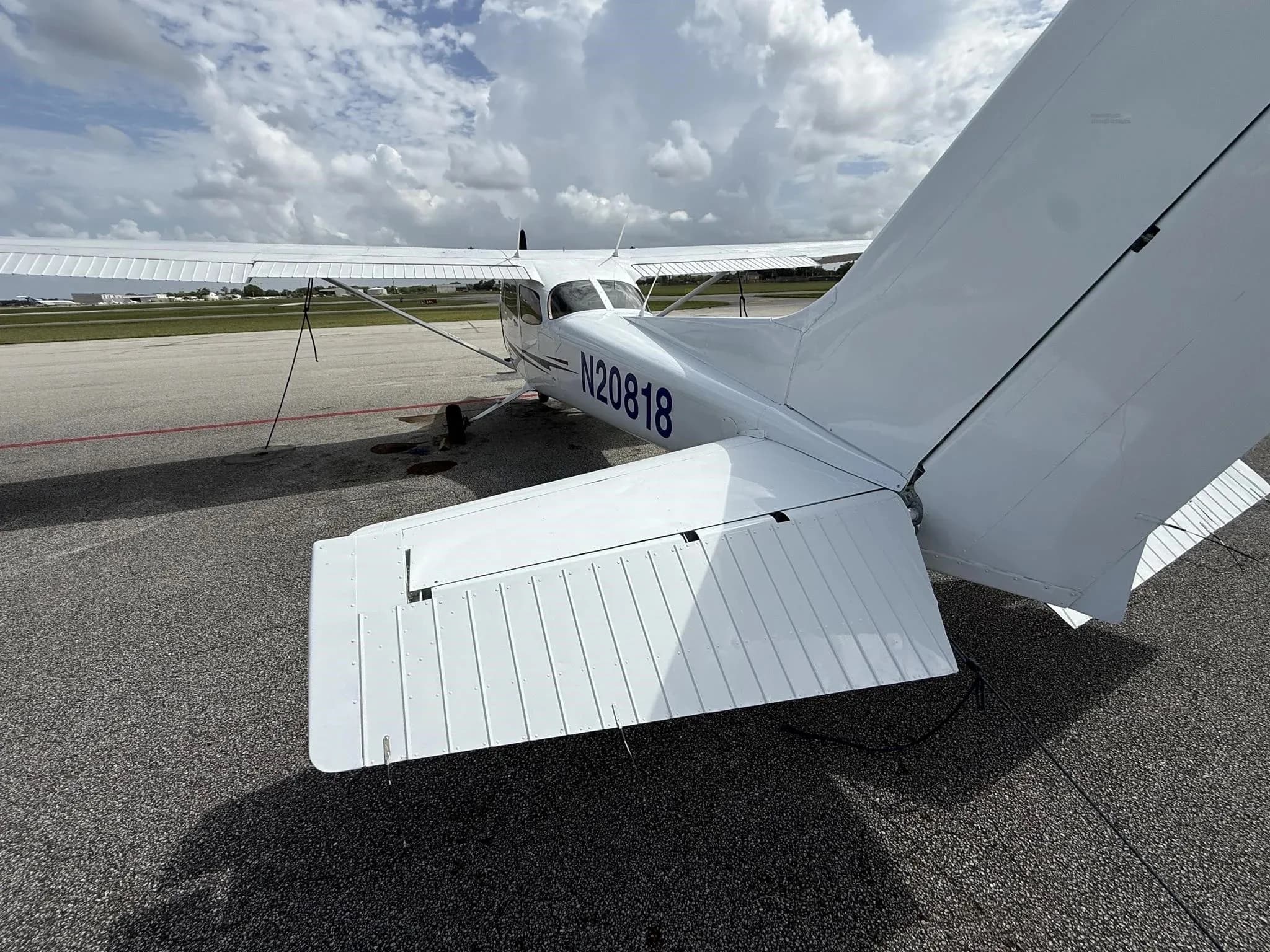 A rear-right view of the white Cessna 172 (N20818) parked on an airport tarmac.