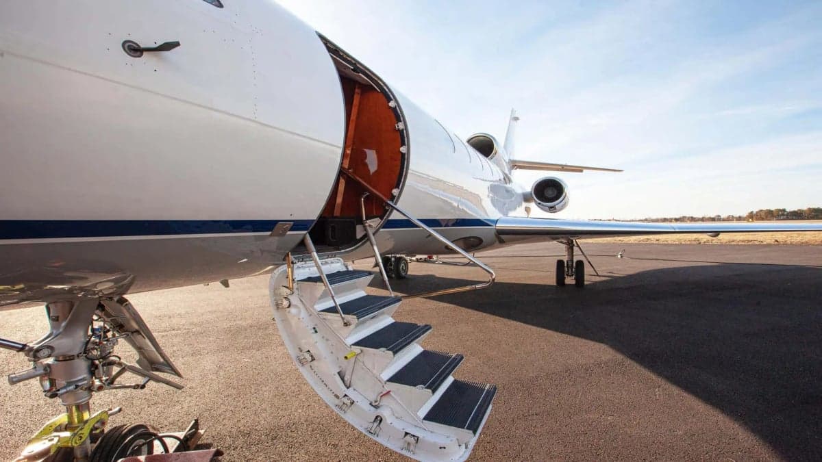 A Falcon jet with the airstair door open on the tarmac.
