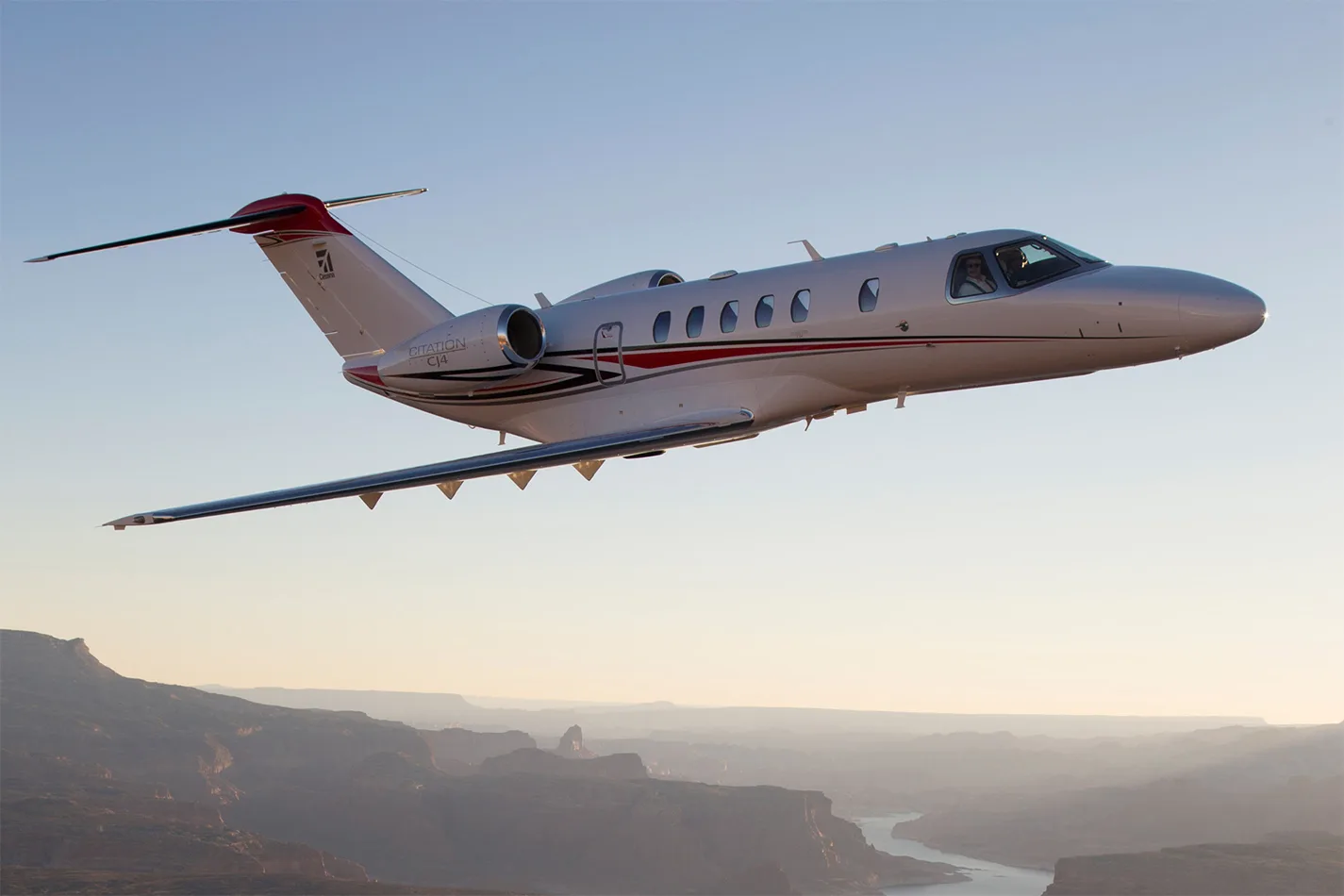 A Citation CJ4 flying over a desert landscape.