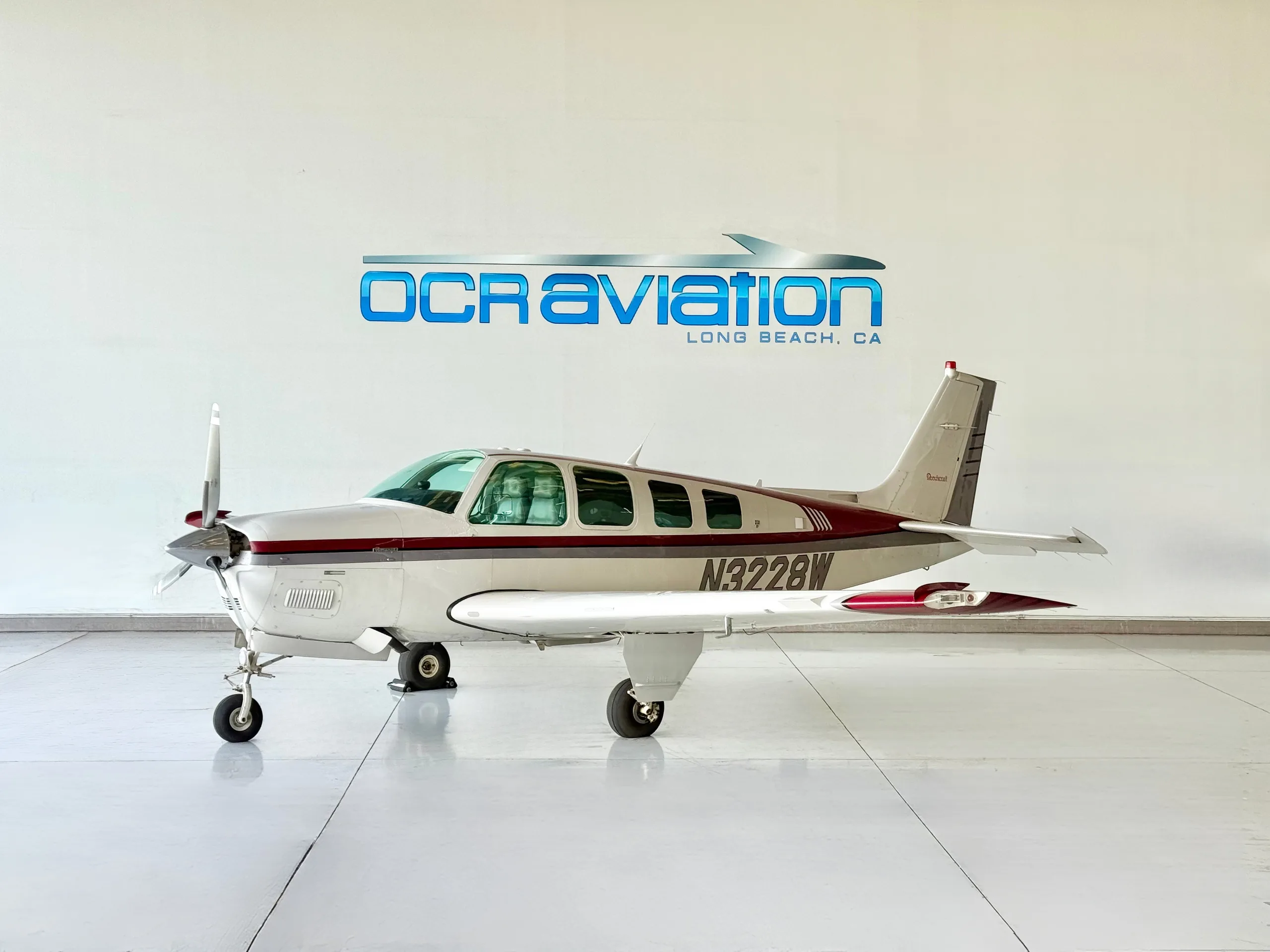 Side view of a Beechcraft Bonanza N3228W in front of a hangar.