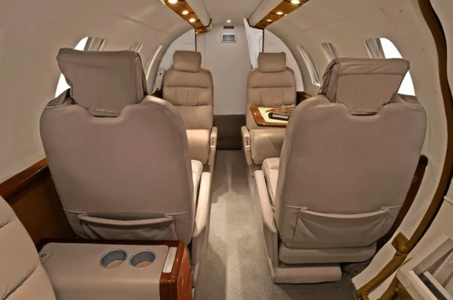 The interior of the aircraft features tan leather seats and wood trim.