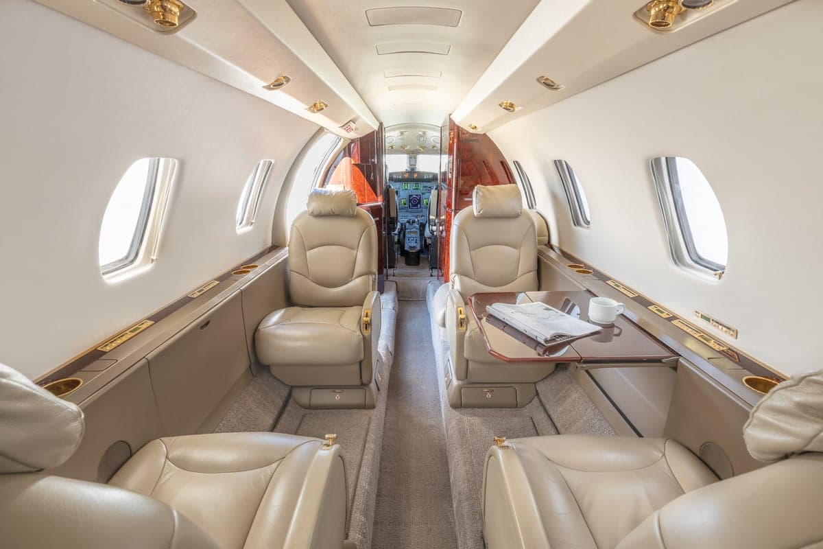 View of the aircraft cabin with tan leather seats and a table.