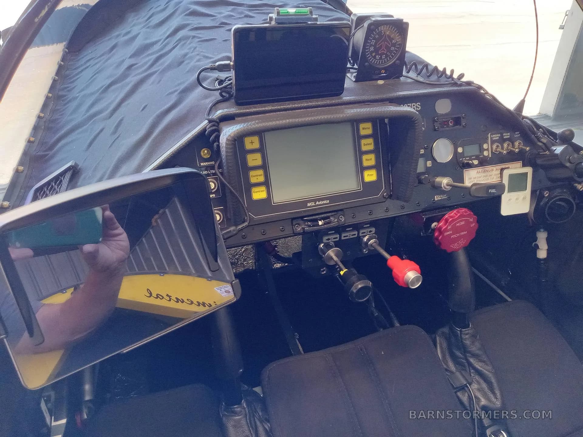 The cockpit of a yellow aircraft, showing the instrument panel with an MGL Avionics display, a GPS unit, and various controls.