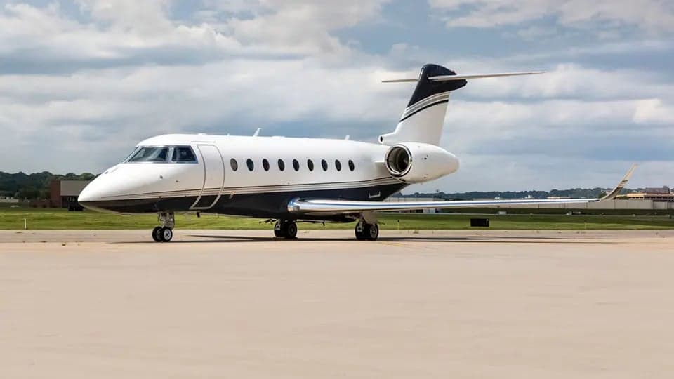 A Gulfstream jet sits on the tarmac with a white and dark blue paint scheme.