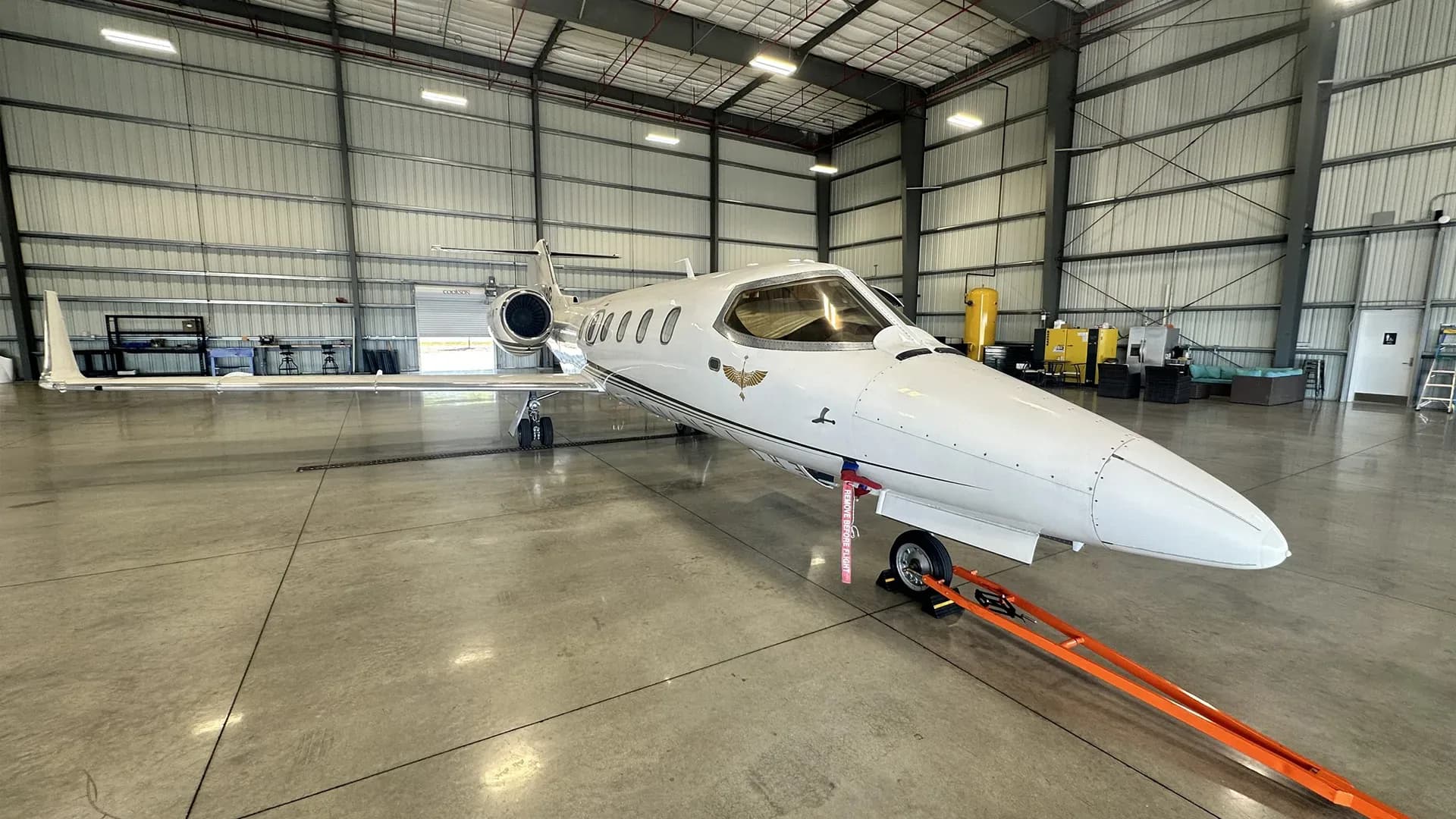 A Learjet 25D aircraft is parked inside a hangar, with tow bar attached to the nose gear.
