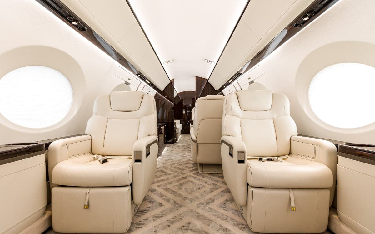 A view down the aisle of the Gulfstream G500 cabin featuring cream-colored leather seats.