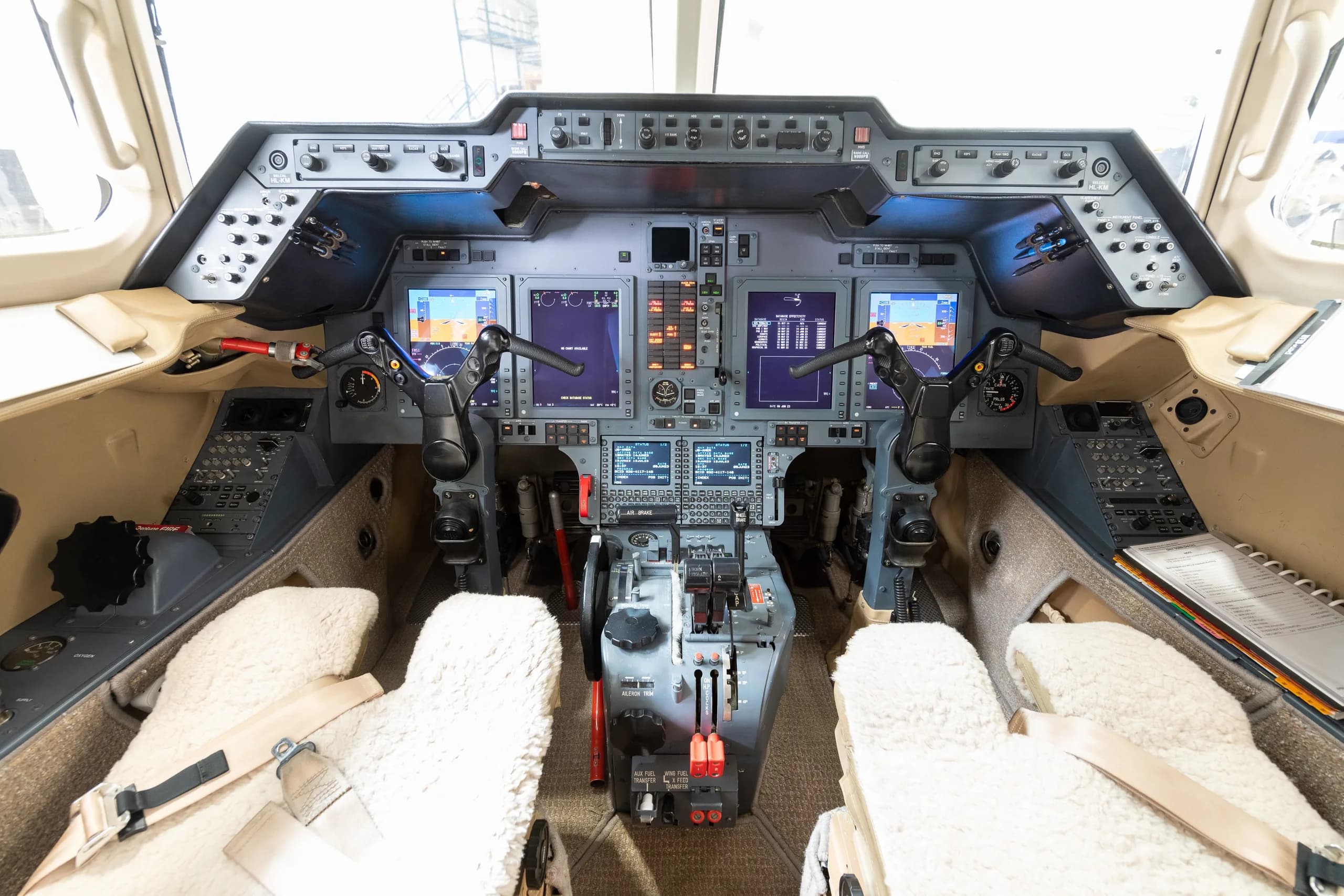The cockpit of a business jet, featuring multiple digital displays and a complex control panel.
