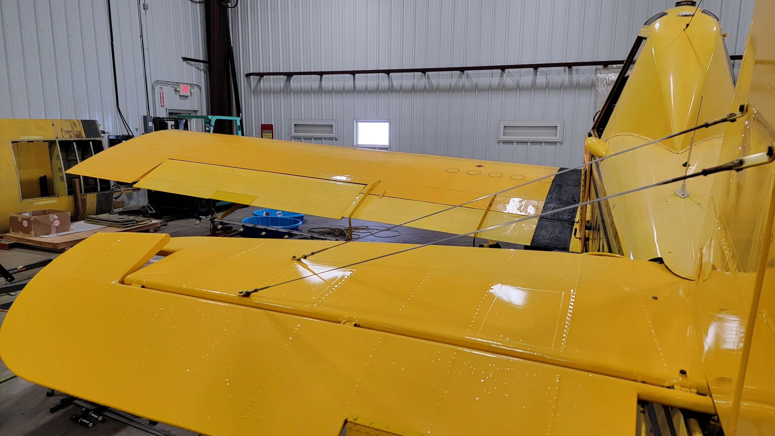 A close-up view of the yellow aircraft's tail section and horizontal stabilizers inside a hangar.