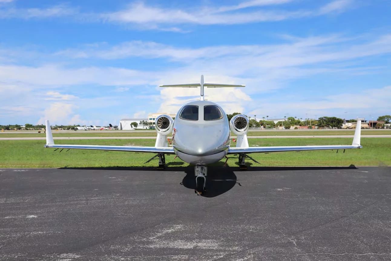 A white and grey HondaJet Elite S (N420XE) parked on a tarmac, viewed head-on from the front.