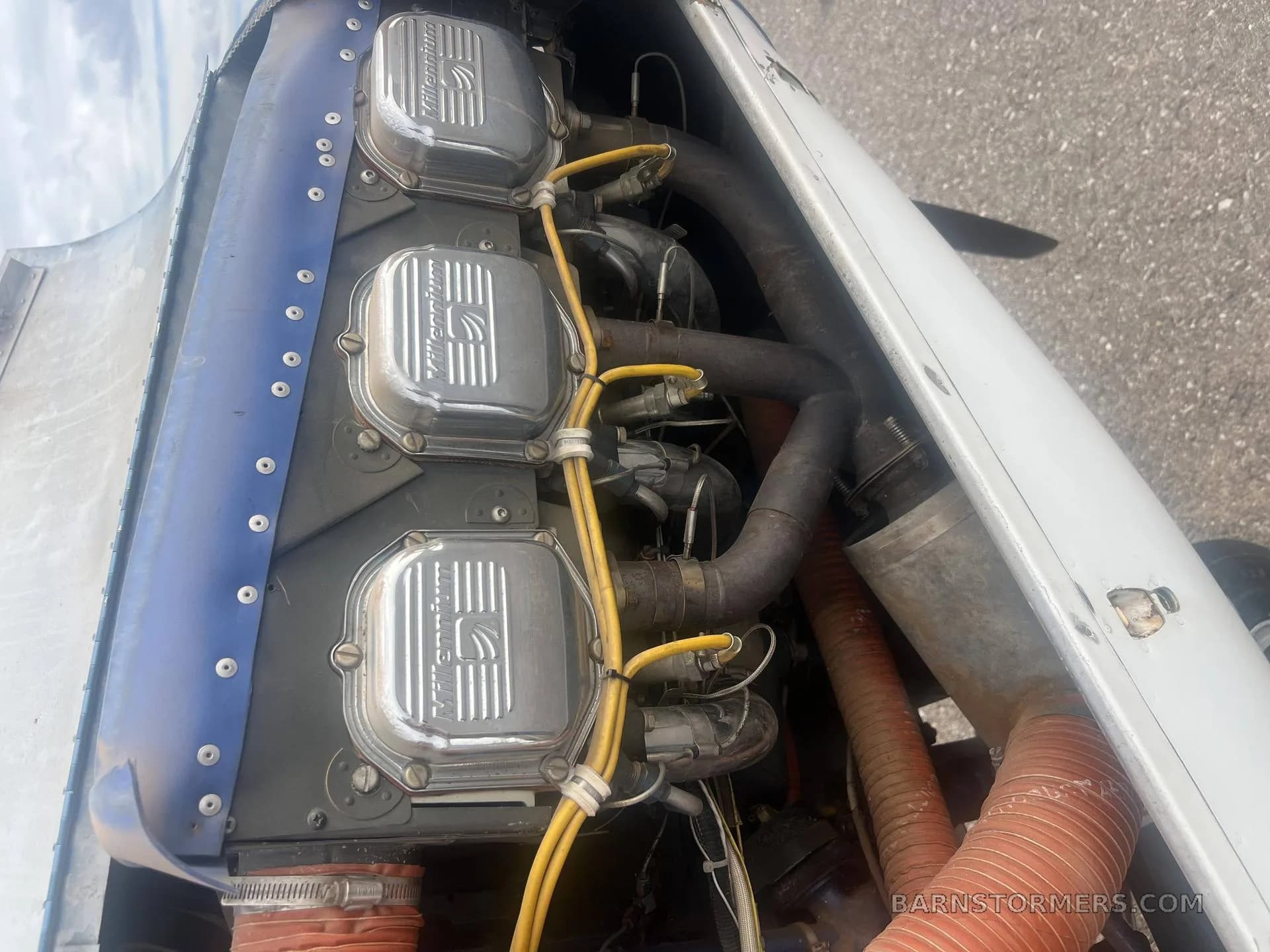 A close-up view of the aircraft's engine, showing three silver cylinder heads with "Continental" branding and yellow ignition wires.